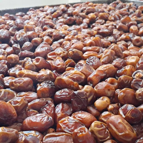 front view xurma brown tasty along with different nuts on the dark background